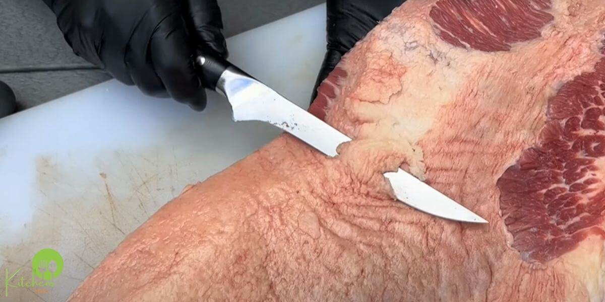 Professional chef using a boning knife to cut meat