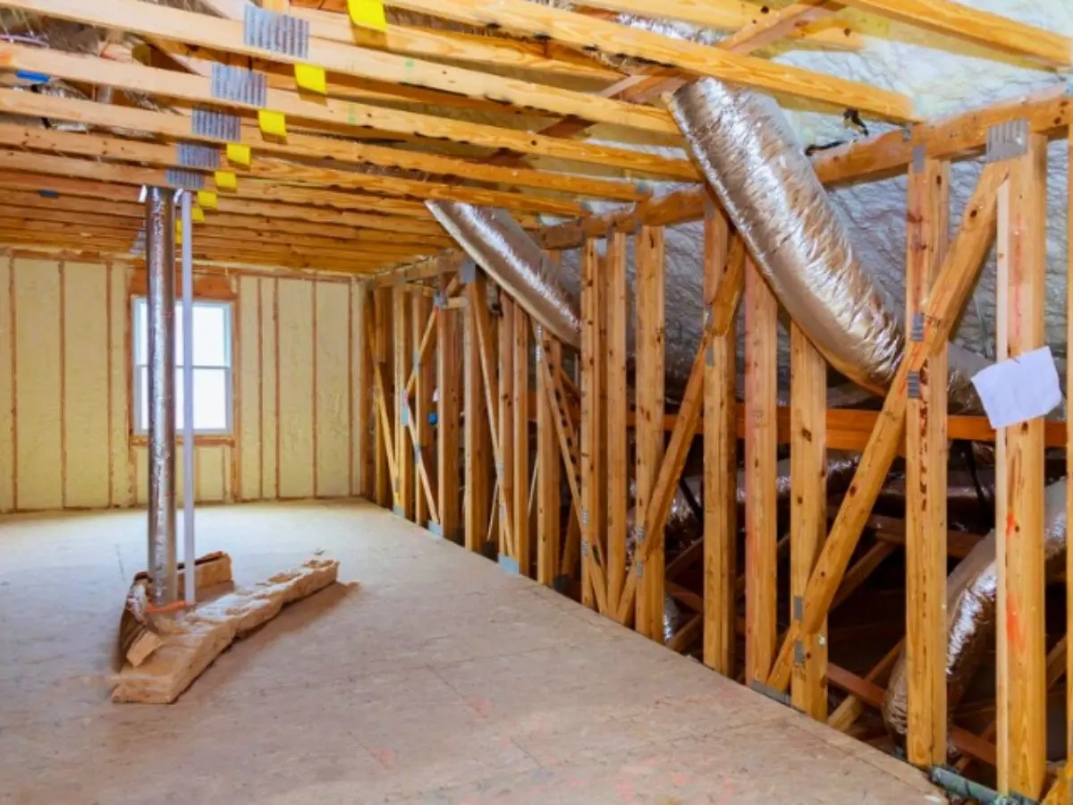 Attic space with HVAC ductwork installed along wooden framing and insulation