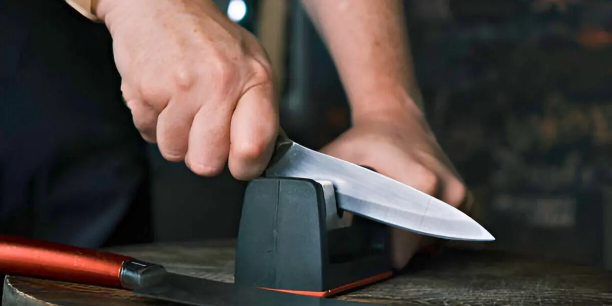 Close-up of a person sharpening a knife using a Chef's Choice 2-stage sharpener